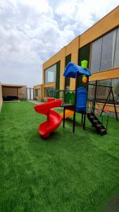 a playground with a slide and a swing at شاليه المنى - الخبر - للعائلات in Al Khobar
