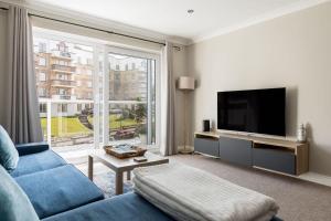 ein Wohnzimmer mit einem blauen Sofa und einem großen Fenster in der Unterkunft Bournemouth Sea Views, 2 Bed, lift, close to shops in Bournemouth