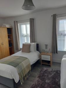 a bedroom with a bed and a table and windows at Mountain Aven Guest House in Doolin