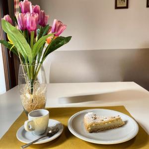 a table with a plate of cake and a vase of flowers at Bevagna VILLA DEL COLLE CAMERA MERLOT in Bevagna