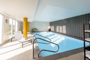 a large swimming pool with blue water in a building at Domitys Les Falaises Blanches in Bayeux