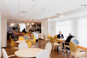 a dining room with people sitting at tables and chairs at Domitys Les Falaises Blanches in Bayeux