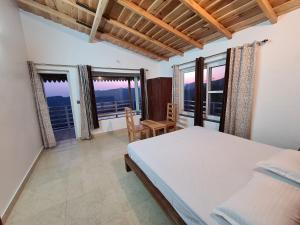 a bedroom with a bed and windows with a view at Abhi's Cottage in Mukteswar