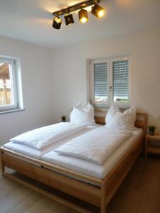 a large bed in a room with two windows at Ferienwohnungen Irmingard in Chieming