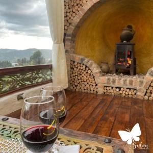 a glass of wine sitting on a table with a fireplace at Cabaña Esmeralda - Seilan Alojamiento Rural in Paipa