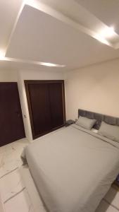 a large white bed in a room with two windows at Mehdia beach one in Kenitra