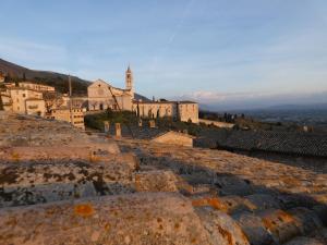 een oud gebouw met een kerk op de achtergrond bij Scappo in Umbria, La casa di Eude in Assisi