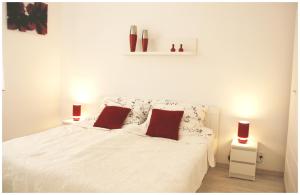 a bedroom with a white bed with two red pillows at Piekary Toruń Apartament in Toruń