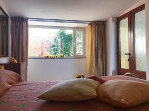 1 dormitorio con cama con almohadas y ventana en Casa fiorita, en SantʼAndrea
