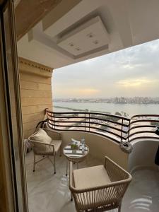 a balcony with chairs tables and a view of the water at Nile view 3 full bedroom apartment in Cairo