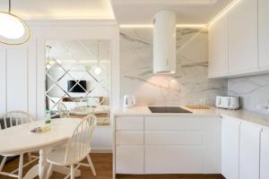 a white kitchen with a white table and chairs at Golden Apartment Prestige with Parking in Warsaw Bemowo in Warszawa