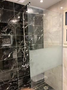 La salle de bains est pourvue d'une douche et d'un mur en marbre noir. dans l'établissement Nile view 3 full bedroom apartment, au Caire