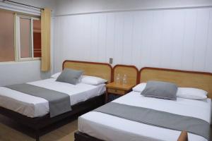a hotel room with two beds and a table at Hotel Riviera in San Juan de los Lagos