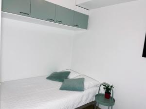 un letto bianco con due cuscini verdi di Docent's Flat a Joensuu
