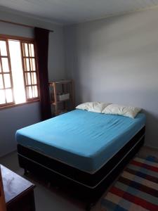 1 dormitorio con 1 cama con sábanas azules y 2 ventanas en Chácaras Sarapui en Sarapuí