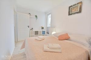 biała sypialnia z 2 ręcznikami na łóżku w obiekcie Sunset Apartments - Green Square + Garaż w Świnoujściu