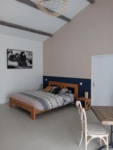 ein Schlafzimmer mit einem Bett, einem Stuhl und einem Tisch in der Unterkunft L'Hacienda in Les Mathes