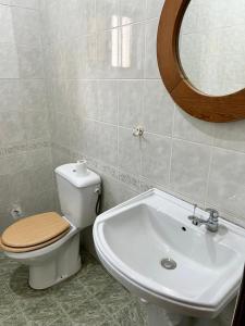 a bathroom with a toilet and a sink and a mirror at VillaXXL & Pool, Fidjrosse, route des pêches, Cotonou in Godomè