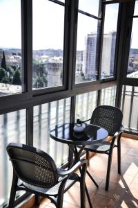 una mesa y 2 sillas en una habitación con ventanas en Horizont Apart-Hotel, en Shkodër
