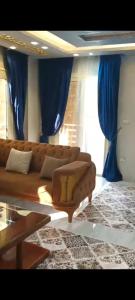 - un salon avec un canapé brun et des rideaux bleus dans l'établissement المهندسين, au Caire