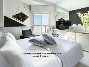 a bedroom with a white bed with a tv and a kitchen at Hotel Michelangelo in Riccione
