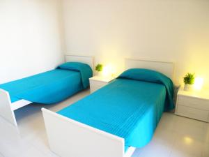 een slaapkamer met 2 bedden met blauwe lakens en 2 tafels bij Casa Carducci in Grado