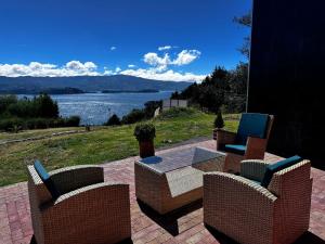 two chairs and a table with a view of a lake at Refugio Lago de Tota in Cuítiva