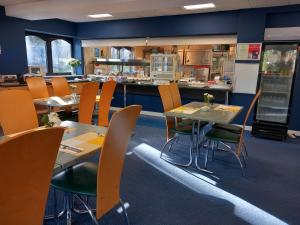 um restaurante com mesas e cadeiras e uma cozinha em Sandown Park Lodge em Esher