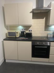 a kitchen with white cabinets and a black stove top oven at Lovely Getaway Apartment in Wisbech in Wisbech