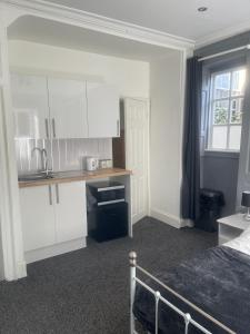 eine Küche mit weißen Schränken und ein Bett in einem Zimmer in der Unterkunft Lovely Getaway Apartment in Wisbech in Wisbech