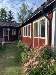 una casa roja con un banco y flores en el patio en Lättillgängligt och trevligt hus en Trosa