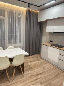 eine Küche mit einem weißen Tisch und weißen Schränken in der Unterkunft Apartaments COSTA 2комн Нурлы жол-62 in Astana