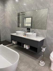 uma casa de banho com 2 lavatórios, uma banheira e um espelho. em Lilitha Boutique Hotel-East London em East London