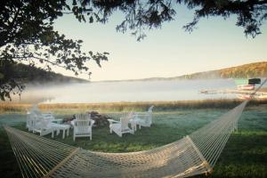 - un hamac dans un champ avec des chaises et un lac dans l'établissement Beautiful Wisconsin Beach Retreat Lake Lucerne, à Crandon