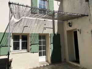 - un bâtiment avec des portes et des fenêtres vertes et blanches dans l'établissement Maison de village, à Lédenon