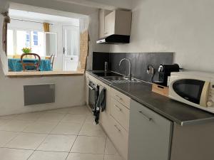 uma cozinha com um lavatório e um micro-ondas em Maison de village em Lédenon