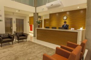 a man standing at a reception desk in a lobby at São Carlos Marklin Suítes in São Carlos