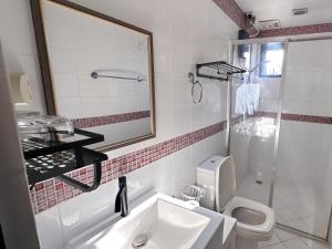 ein Badezimmer mit einem Waschbecken, einem WC und einem Spiegel in der Unterkunft LarisZone-Luxury Courtyard Villa in Manila