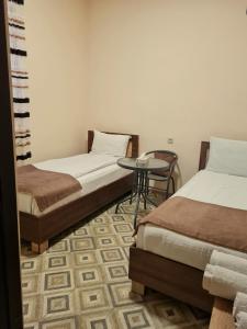 a room with two beds and a table in it at Budget Hotel Rooms In Yerevan in Yerevan