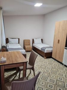 a room with two beds and a table and chairs at Budget Hotel Rooms In Yerevan in Yerevan