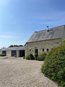 a large stone building with windows and a driveway at La Forge, gîte familial,à Sainte Mère Eglise in Sainte-Mère-Église