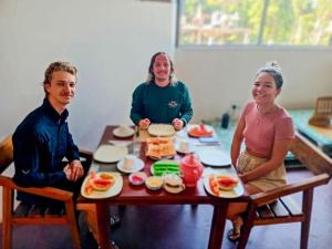 three people sitting around a table with food on it at Eyeful Ella Hostel in Ella