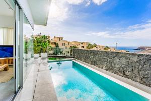 a house with a swimming pool and a stone wall at Villa Larisa in Callao Salvaje