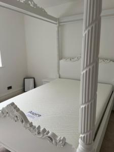a white bed in a white room with columns at The hidden cottage in Wythenshawe