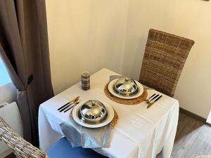 une table blanche avec des assiettes et des plats en argent dans l'établissement La Glycine, à Chamoux-sur-Gelon