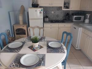 eine Küche mit einem weißen Tisch mit Stühlen und einem weißen Kühlschrank in der Unterkunft Charmante maison au calme in Marzan