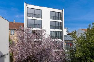 ein weißes Gebäude mit einem blühenden Baum davor in der Unterkunft Grand appartement moderne très proche de Paris centre in Malakoff