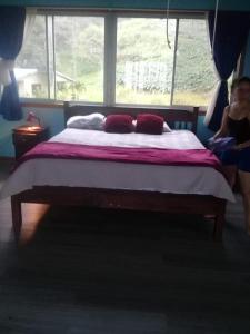 Eine Frau, die in einem Schlafzimmer auf einem Bett sitzt. in der Unterkunft Butterfly Dance studio apartment, San Ramon in Santiago
