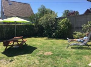 a man sitting in a chair under an umbrella in a yard at maisonnette in Dieppe +3 photos