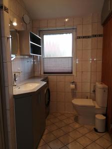 ein Bad mit einem Waschbecken, einem WC und einem Fenster in der Unterkunft Ferienhaus Kormoran in Otterndorf